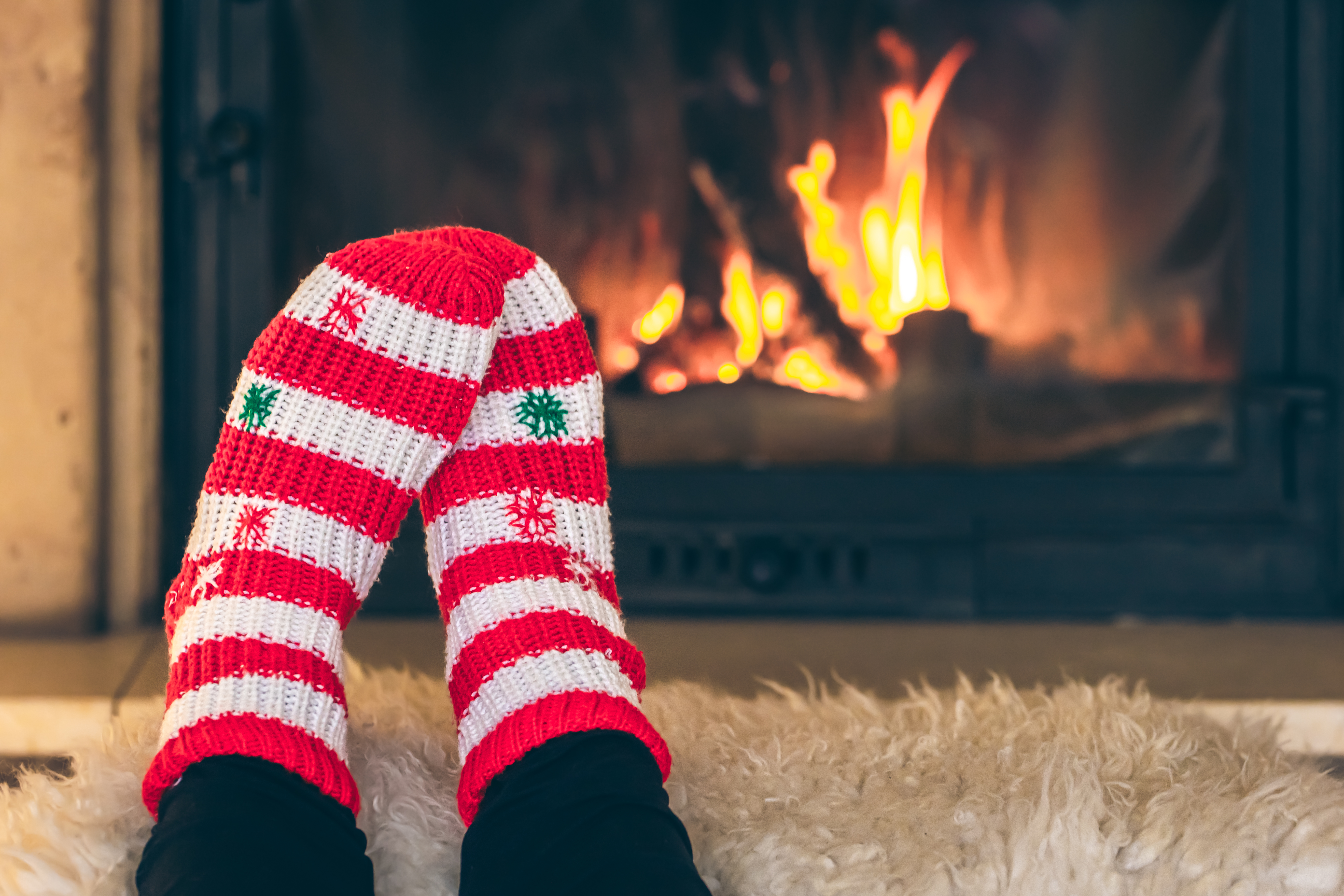 feet with holiday socks getting warm in front of fireplace